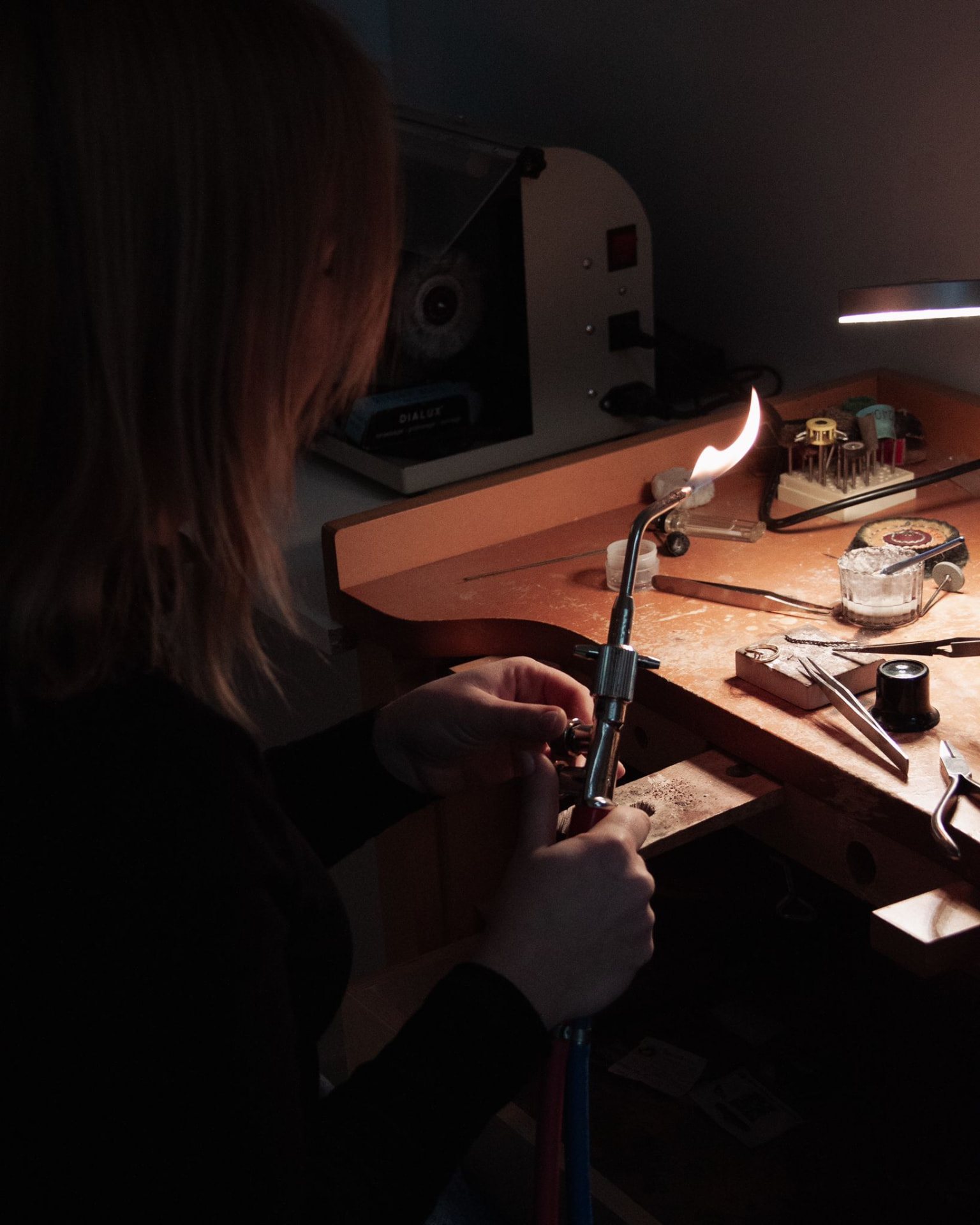 Feliz soldeert een juweel met de brander aan de werkbank