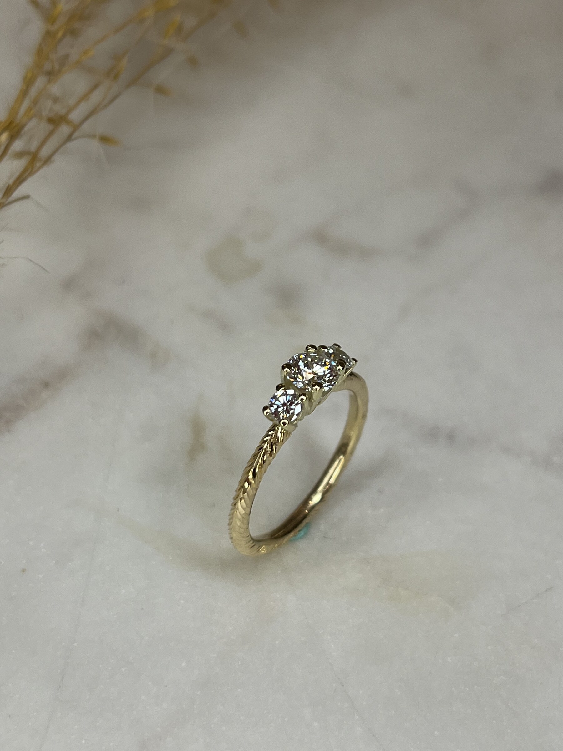 Geelgouden verlovingsring met drie diamanten en gegraveerde ringband